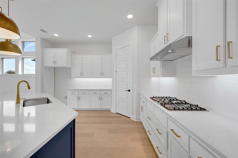 Kitchen featuring white cabinetry, light stone counters, light wood-type flooring, and stainless steel gas cooktop