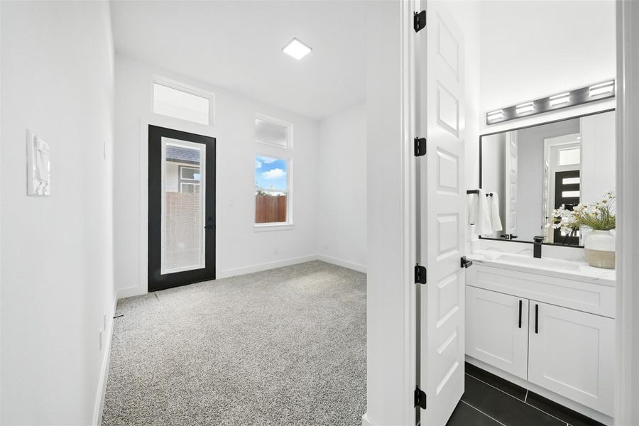 Flexible first-floor room with modern finishes, perfect for a home office, guest bedroom, or flex space. Features plush carpet, natural light from multiple windows, and a door leading to a side yard with a covered patio—plus convenient access to a nearby bathroom for added comfort and functionality. Flexible first-floor room with modern finishes, perfect for a home office, guest bedroom, or flex space. Features plush carpet, natural light from multiple windows, and a door leading to a side yard with a covered patio—plus convenient access to a nearby bathroom for added comfort and functionality.