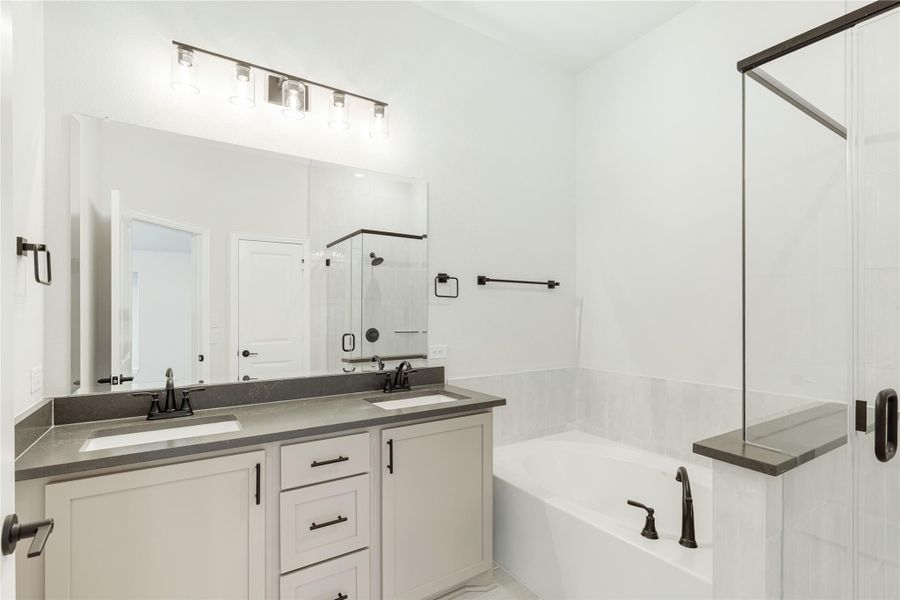 Bathroom with double sink vanity, soaking tub, and glass shower enclosure with dark hardware accents