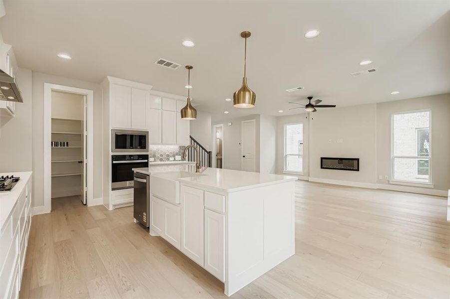 Kitchen featuring stainless steel appliances, recessed lighting, white cabinetry, light wood-style flooring, and light countertops