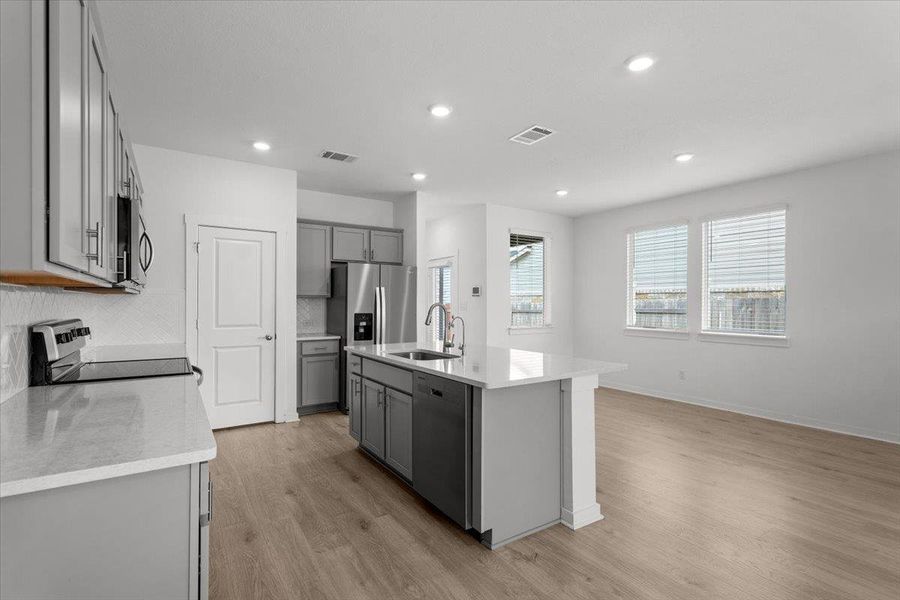A well-appointed kitchen island anchors this open-concept living space, featuring contemporary cabinetry and a suite of stainless steel appliances.
