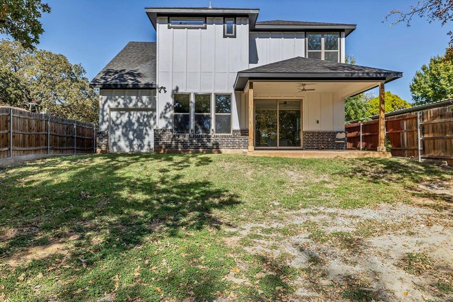 Rear view of house with a patio, a fenced backyard, brick siding, and a shingled roof