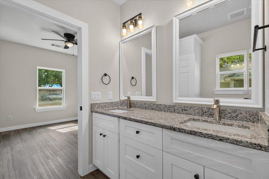 Granite counters and double sinks anchor this well-appointed bathroom featuring clean lines and dual mirrors. Granite counters and double sinks anchor this well-appointed bathroom featuring clean lines and dual mirrors.