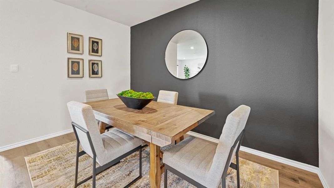 Dining area featuring hard surface flooring, a dark accent wall, and a wooden table Dining area featuring hard surface flooring, a dark accent wall, and a wooden table