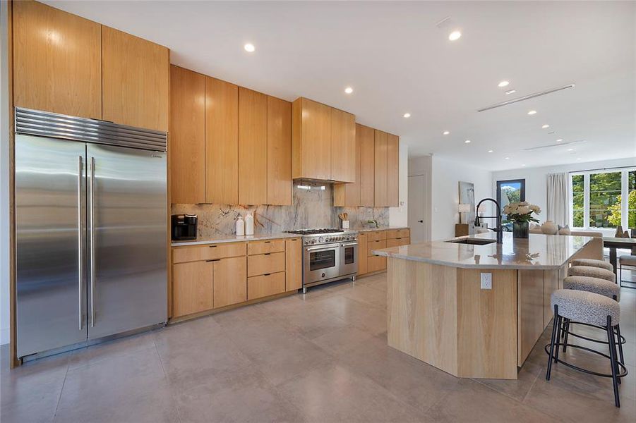 Kitchen with sink, high quality appliances, backsplash, a breakfast bar area, and a kitchen island with sink