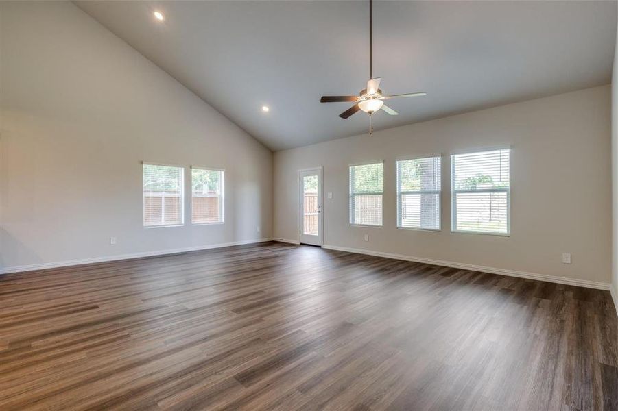 Unfurnished living room with ceiling fan, dark hardwood / wood-style floors, and high vaulted ceiling