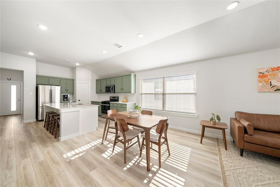 Dining area with sink, vaulted ceiling, and light hardwood / wood-style flooring