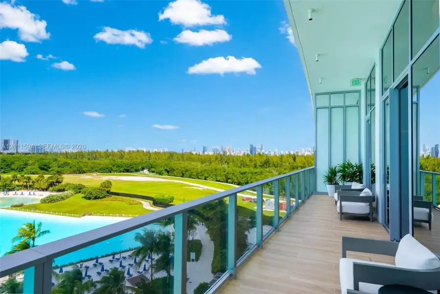 Covered balcony featuring wood-finish flooring, full-height glass panel railings, and floor-to-ceiling glass wall panels Covered balcony featuring wood-finish flooring, full-height glass panel railings, and floor-to-ceiling glass wall panels