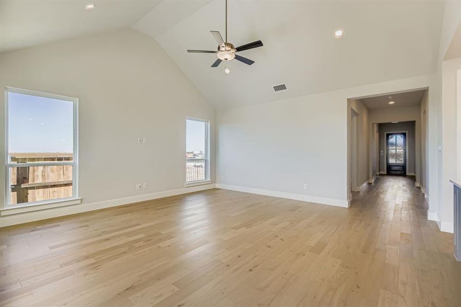 Unfurnished living room with high vaulted ceiling, ceiling fan, light wood-style floors, and recessed lighting