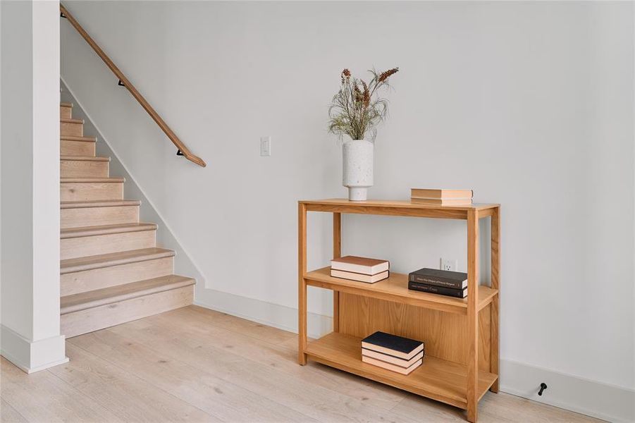 Light wood-finish flooring extending from the entryway to the staircase