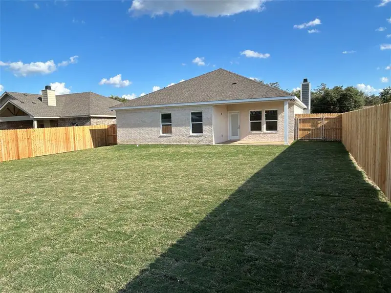 Back of property with a patio area, a fenced backyard, a chimney, brick siding, and a shingled roof