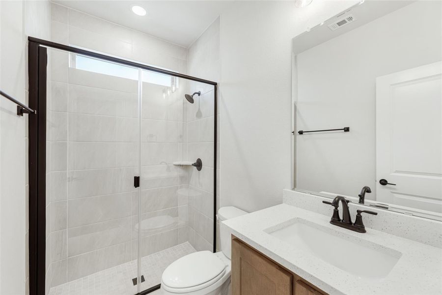 Bathroom with glass-enclosed tile shower, single vanity with quartz countertop, and dark bronze fixtures