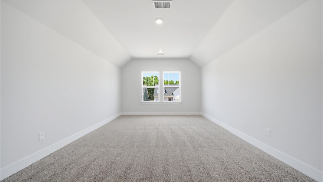 Memorable upstairs bonus room with plush carpeting and a bright, welcoming atmosphere at the Iris Meadows community