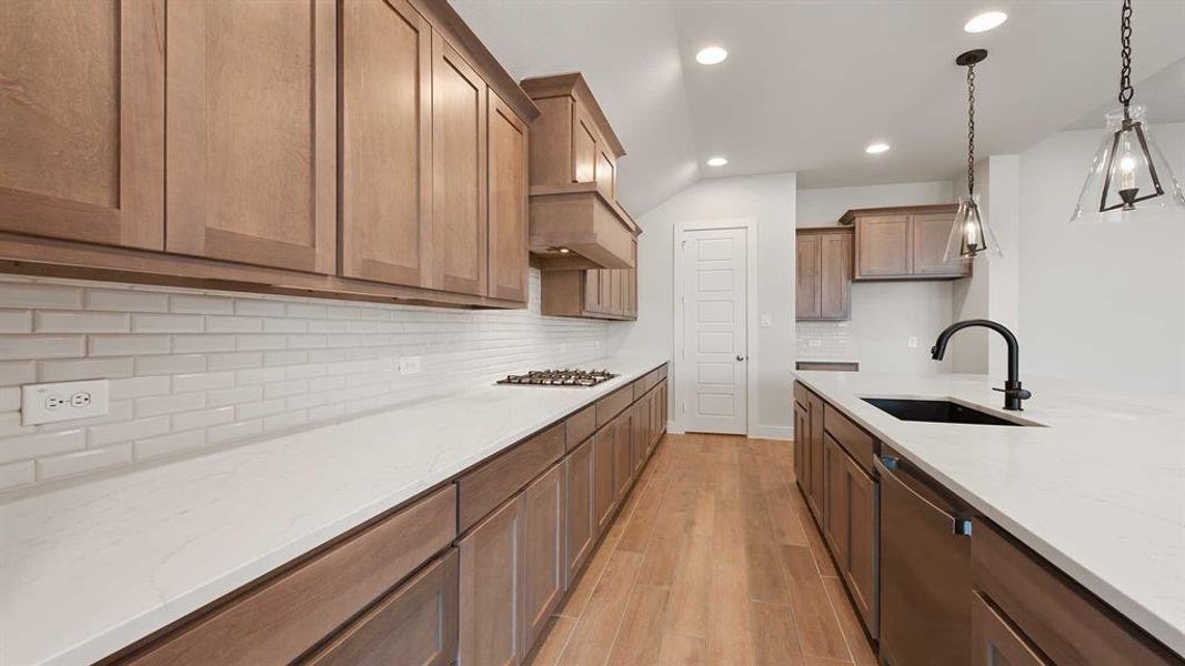 Kitchen with sink, decorative light fixtures, light wood-type flooring, stainless steel appliances, and light stone countertops