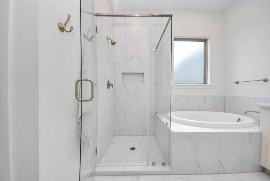 Luxurious bathroom with a spacious glass-enclosed shower and a relaxing soaking tub, featuring elegant marble tile and modern fixtures.