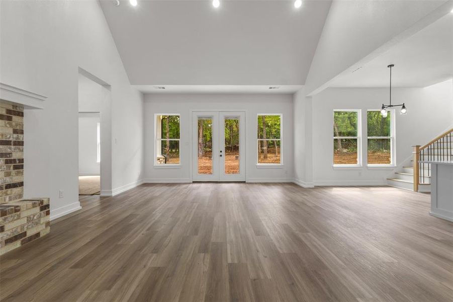 Spacious interior with vaulted ceilings, light wood-look flooring, and a brick fireplace