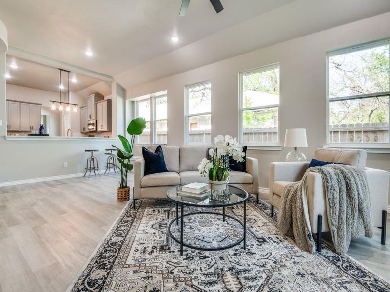 Living room featuring light wood-style floors, ceiling fan, baseboards, and a healthy amount of sunlight Living room featuring light wood-style floors, ceiling fan, baseboards, and a healthy amount of sunlight