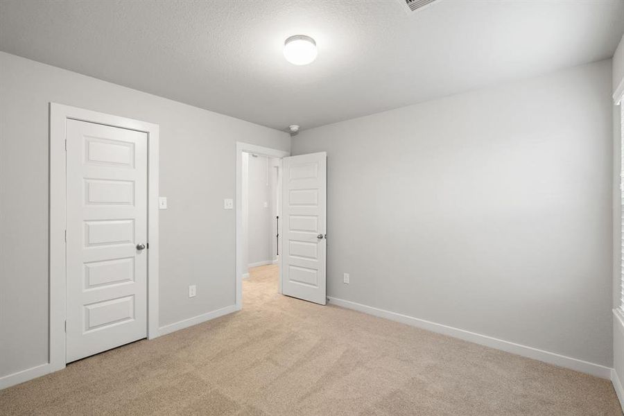 Generously sized secondary bedrooms, showcasing 5-panel doors with modern hardware, large windows adorned with privacy blinds, and spacious closets boasting sleek and contemporary finishes. Representation. Actual color and selections can vary.