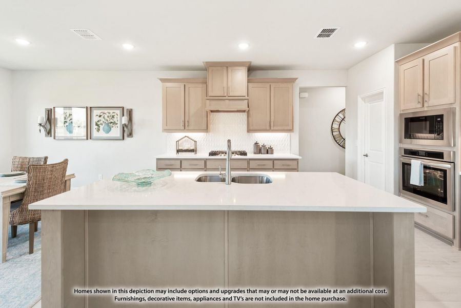 Kitchen with large island, white countertops, light wood cabinets, and stainless steel appliances