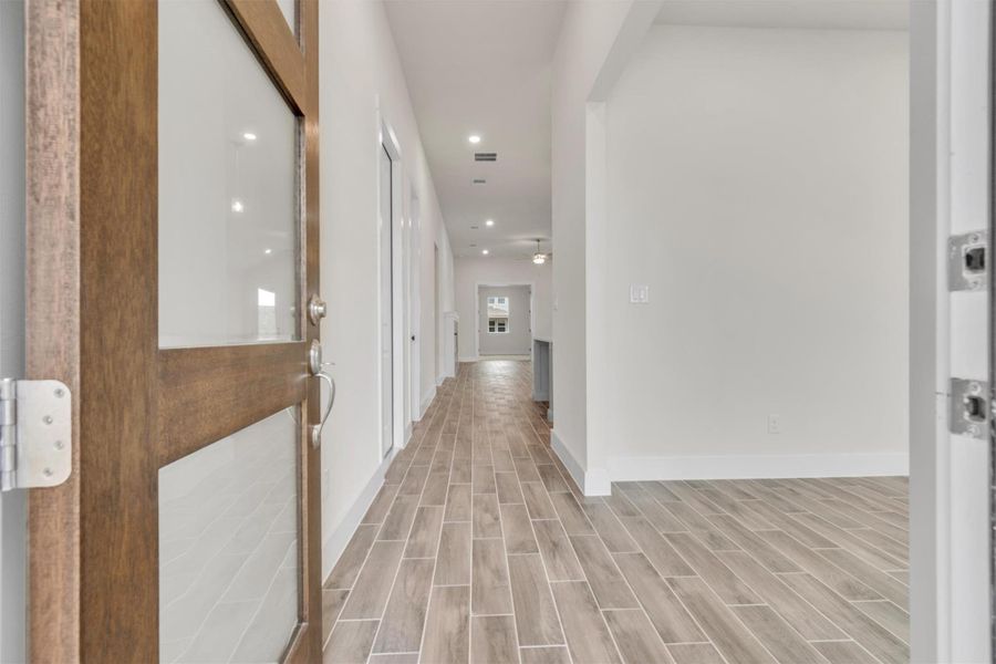 A well-lit entry hall with wood-look tile flooring leads to the home's interior.
