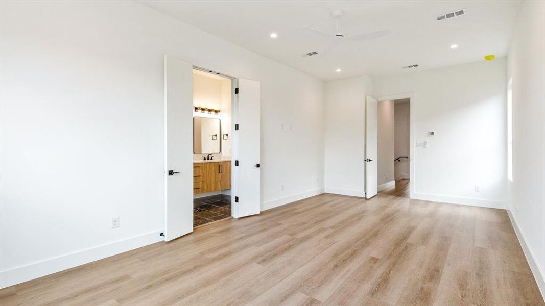 Unfurnished bedroom featuring ensuite bath, ceiling fan, sink, and light hardwood / wood-style floors