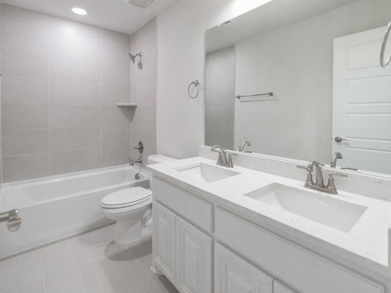 Full bathroom featuring vanity, tile patterned floors, toilet, and tiled shower / bath