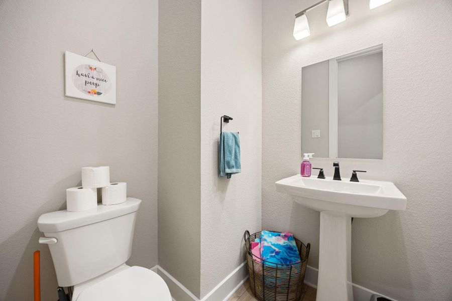 This half bath offers a clean and functional design with neutral tones, a pedestal sink, and modern lighting. The layout provides both style and convenience, perfect for guests or everyday use.