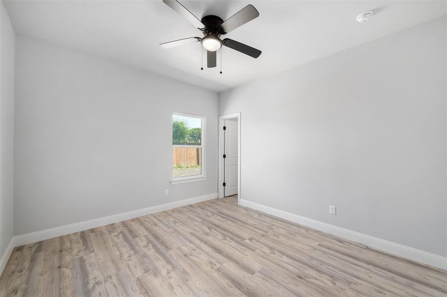 Spare room featuring ceiling fan, baseboards, and light wood-type flooring