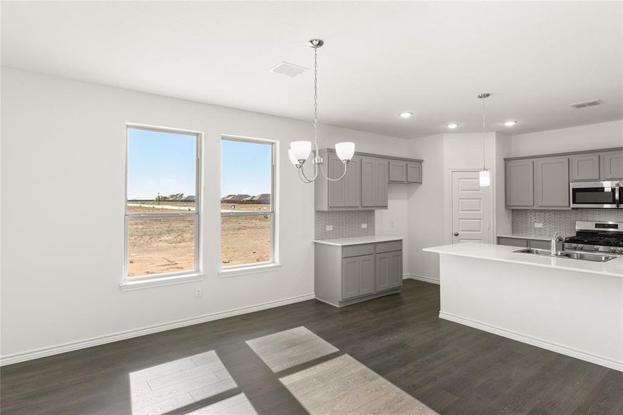 Kitchen featuring tasteful backsplash, appliances with stainless steel finishes, dark hardwood / wood-style floors, and hanging light fixtures