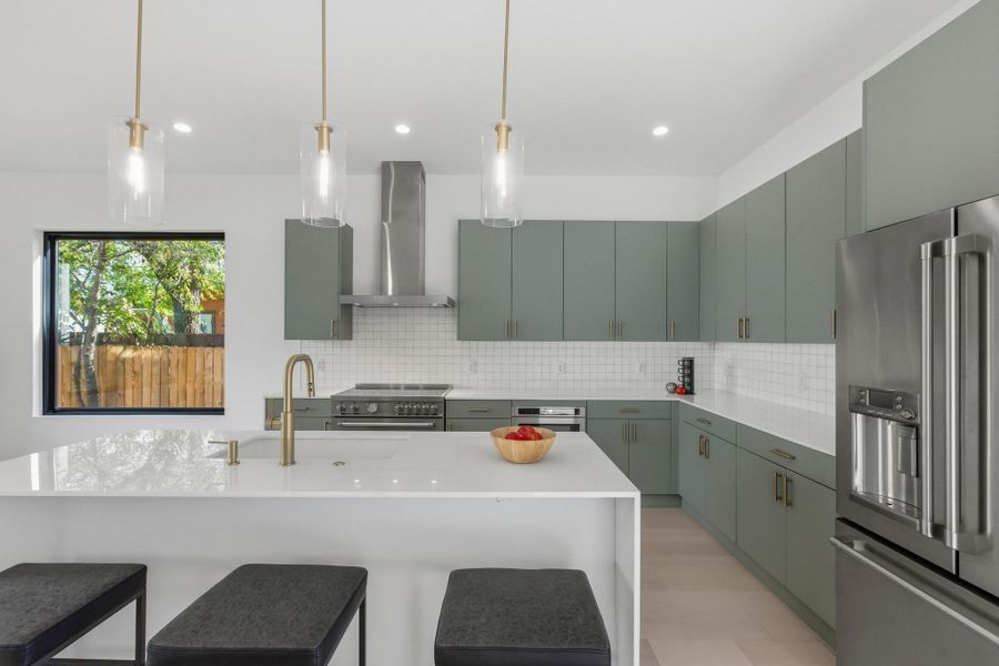 Kitchen with high quality appliances, a kitchen island with sink, decorative light fixtures, a breakfast bar, and recessed lighting