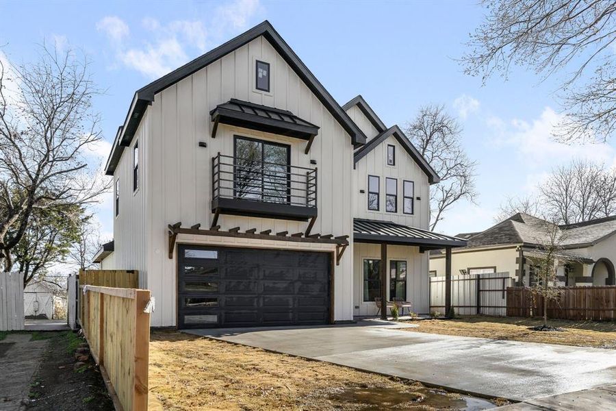 Modern inspired farmhouse featuring a balcony, fence, concrete driveway, board and batten siding, and a standing seam roof