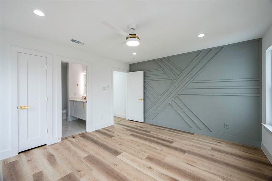 Unfurnished bedroom featuring connected bathroom, ceiling fan, and light wood-type flooring