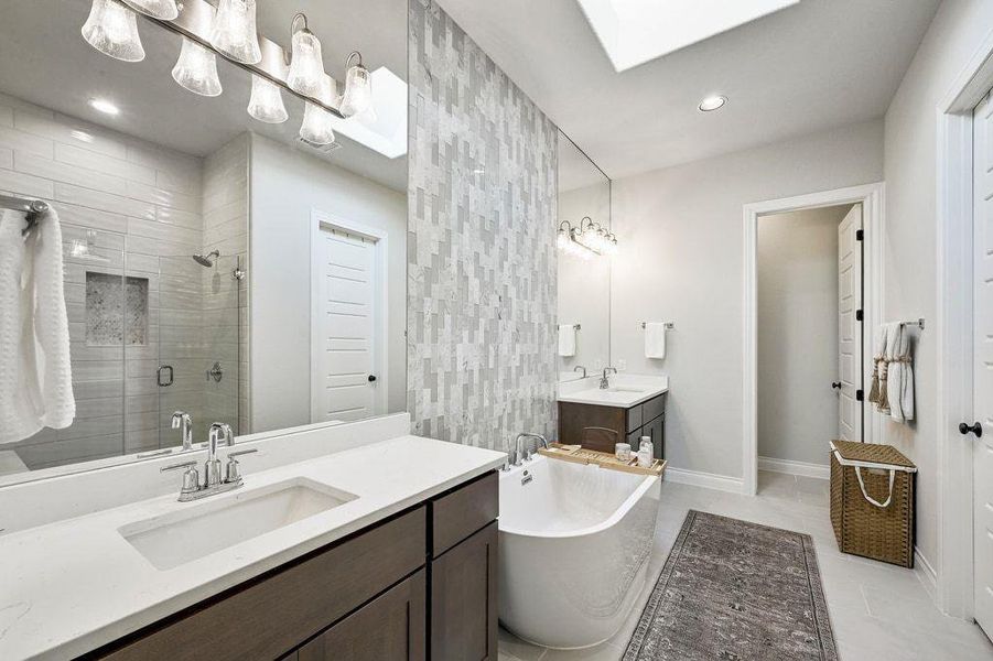 Primary bathroom with two vanities, a shower stall, a soaking tub, a skylight, mirrors to the ceiling, extensive tile work and recessed lighting Primary bathroom with two vanities, a shower stall, a soaking tub, a skylight, mirrors to the ceiling, extensive tile work and recessed lighting