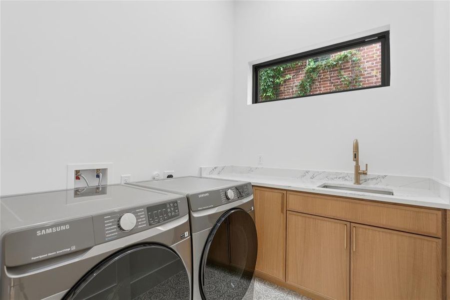 Utility room featuring wood-finish cabinetry, a single basin sink with a gold-tone faucet, and a horizontally oriented window Utility room featuring wood-finish cabinetry, a single basin sink with a gold-tone faucet, and a horizontally oriented window