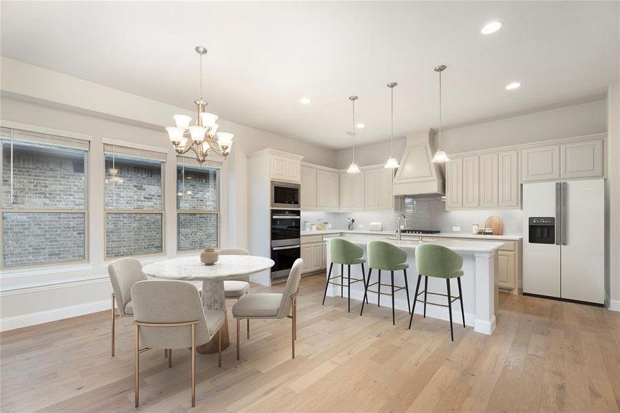 Kitchen featuring a breakfast bar area, appliances with stainless steel finishes, an island with sink, tasteful backsplash, and light wood-type flooring