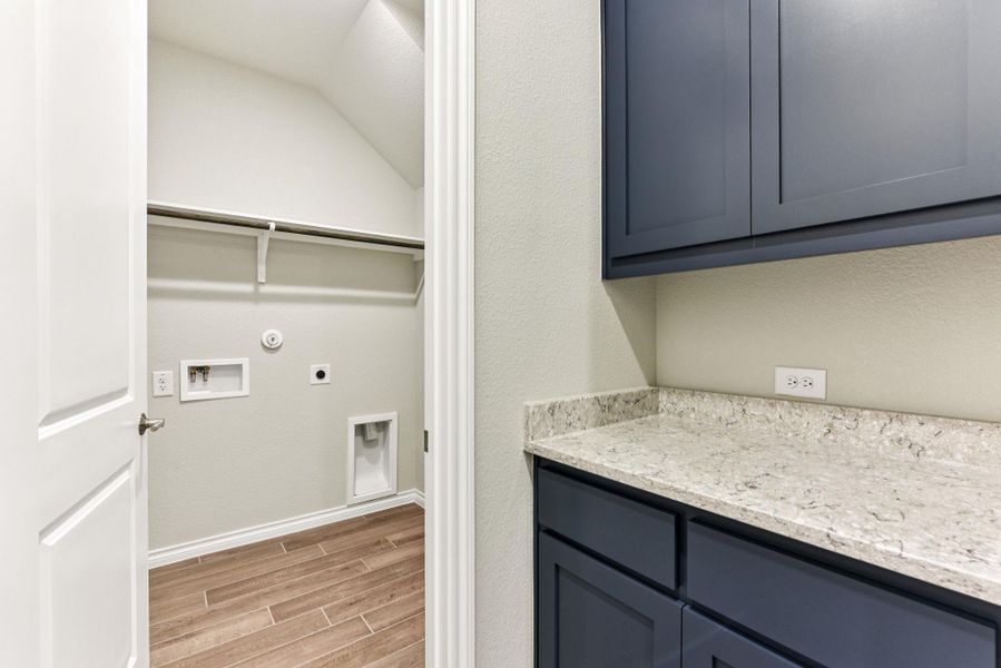 Washroom with wood finish floors, hookup for a gas dryer, electric dryer hookup, and hookup for a washing machine Washroom with wood finish floors, hookup for a gas dryer, electric dryer hookup, and hookup for a washing machine