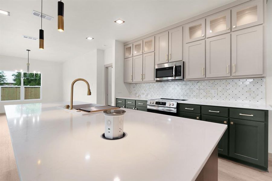 Kitchen featuring visible vents, a center island with sink, tasteful backsplash, appliances with stainless steel finishes, and decorative light fixtures