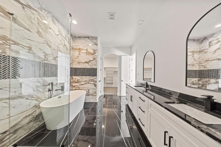 Bathroom with a soaking tub, a spacious closet, double vanity, dark marble finish flooring, and recessed lighting Bathroom with a soaking tub, a spacious closet, double vanity, dark marble finish flooring, and recessed lighting