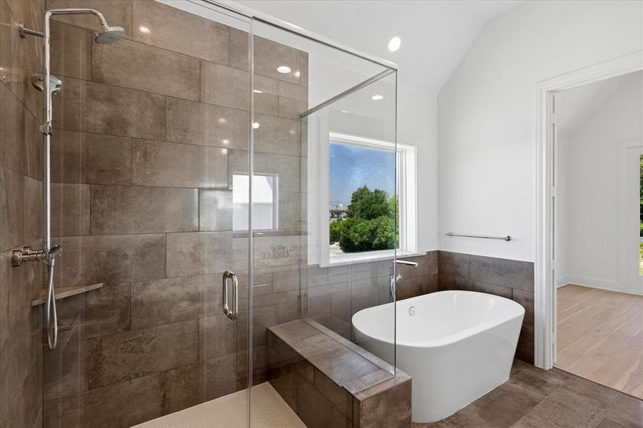 Contemporary bathroom featuring a spacious walk-in shower with a built-in bench, a freestanding soaking tub, and large format wall and floor tiling