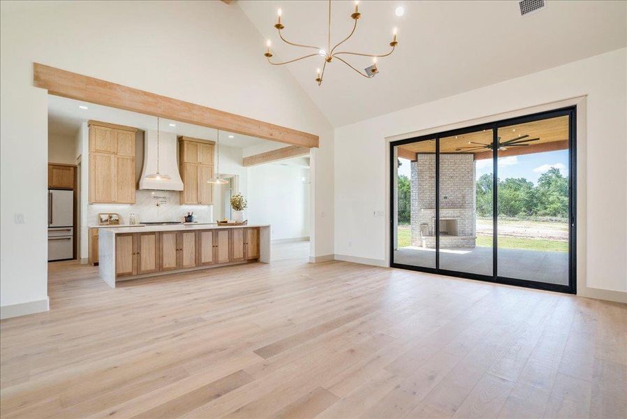 A spacious, open concept living area boasts a modern kitchen and views of the outdoor fireplace through sliding glass doors.