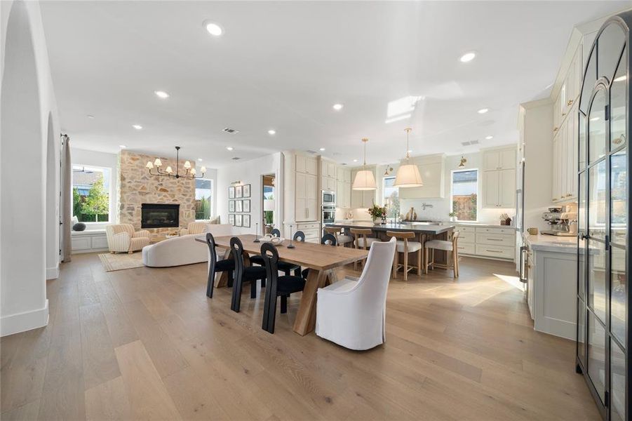 Dining space with a fireplace, an inviting chandelier, and light hardwood / wood-style flooring