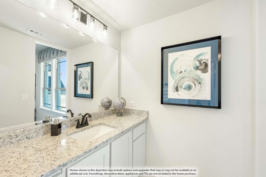 Bathroom vanity with granite countertop, white cabinets, single sink, and large mirror with overhead lighting
