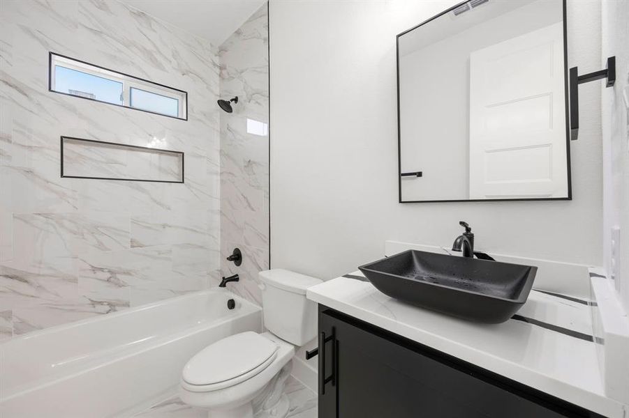 Modern bathroom featuring a black vessel sink set on a white countertop with black accent striping Modern bathroom featuring a black vessel sink set on a white countertop with black accent striping