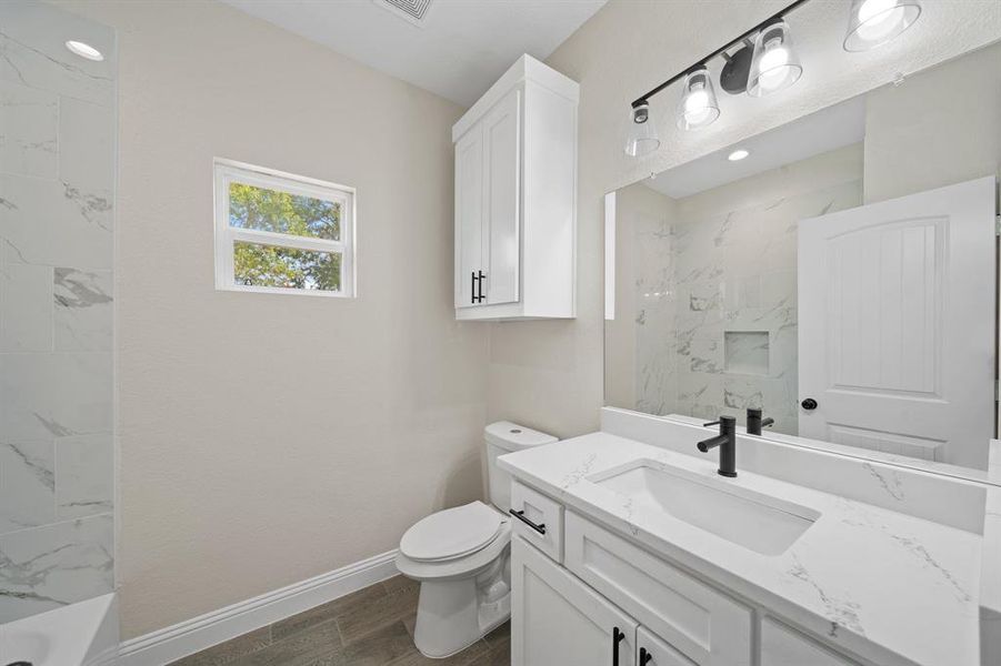 Full bathroom featuring vanity, tiled shower / bath combo, toilet, and hardwood / wood-style flooring