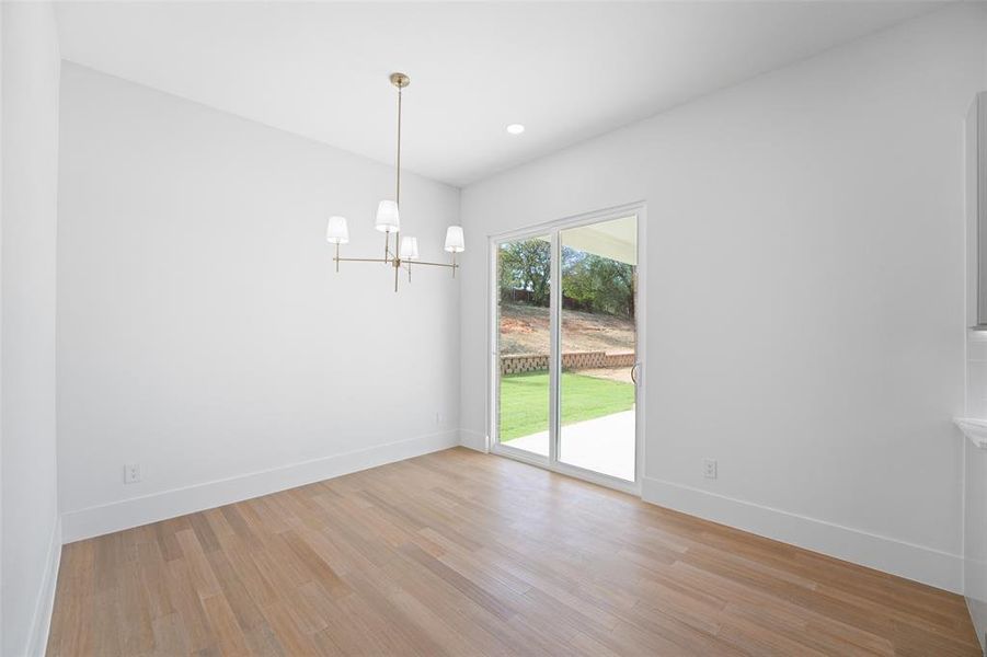 Unfurnished dining area featuring a chandelier, light wood finished floors, and recessed lighting