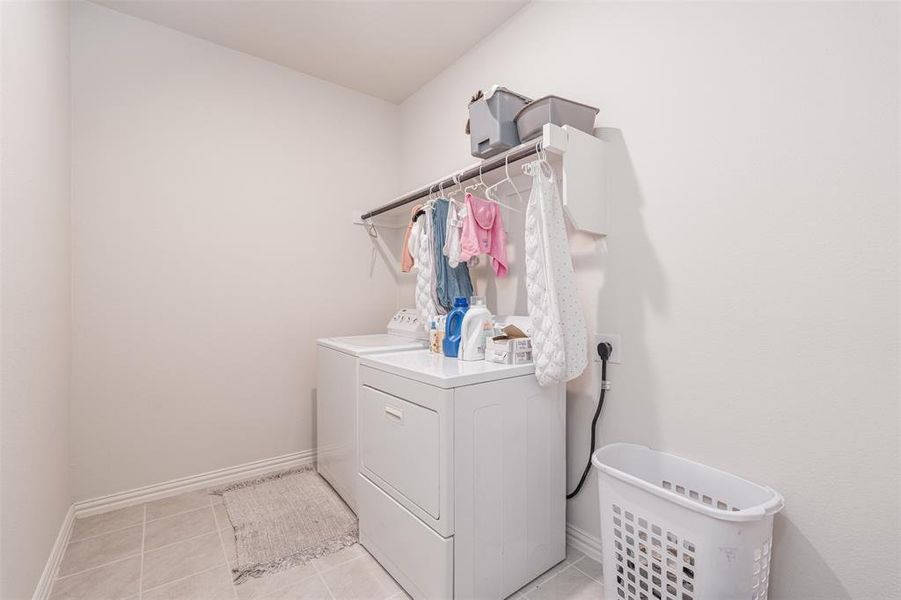 Laundry room with laundry area, light tile patterned floors, baseboards, and washer and dryer