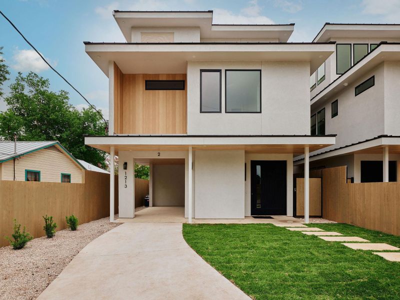 Modern exterior featuring white stucco, wood-finish siding, and black-framed windows