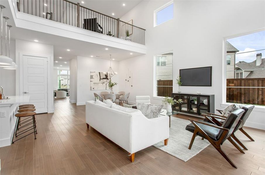 Living room with an inviting chandelier, hardwood / wood-style floors, and a towering ceiling