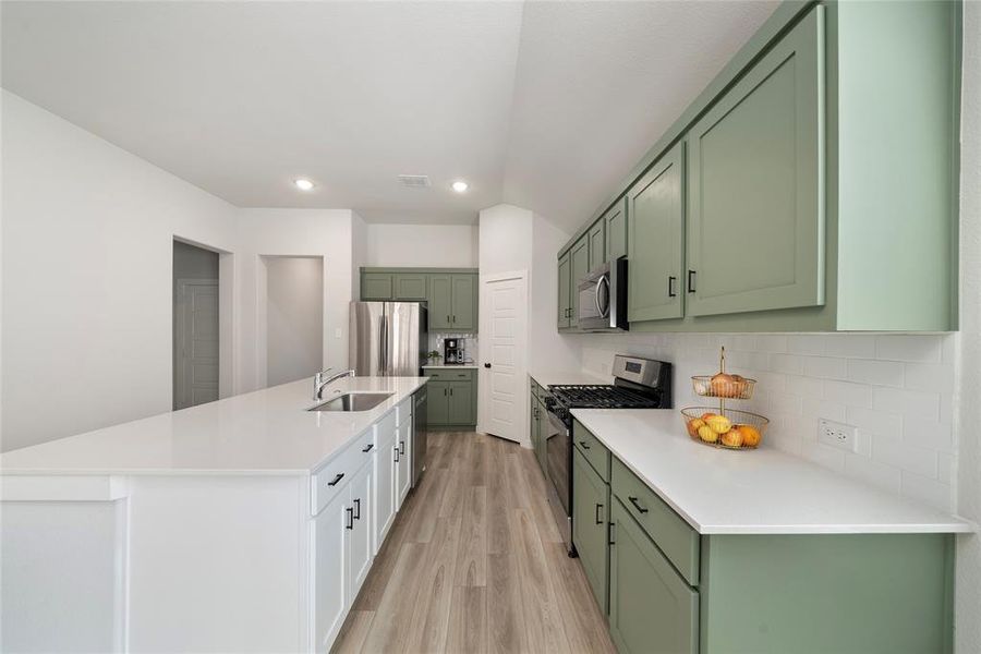 Kitchen with sink, stainless steel appliances, tasteful backsplash, and green cabinetry