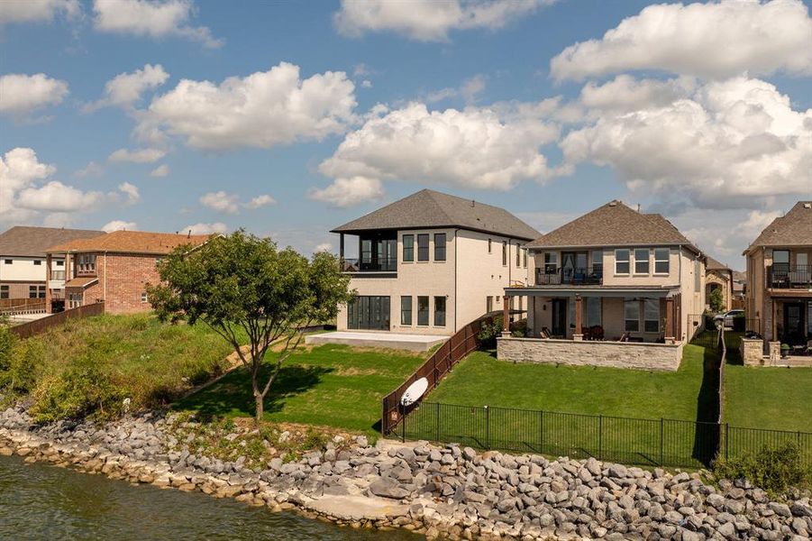 Back of house featuring a fenced backyard, a patio, a balcony, a water view, and a residential view